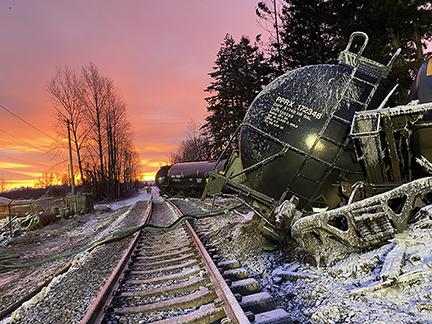 Derailed train sitting next to track in the sunset