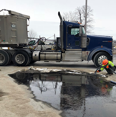 person cleaning up a spill outside in front of a truck