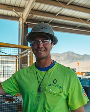 A man in a hardhat and neon green shirt smiling 